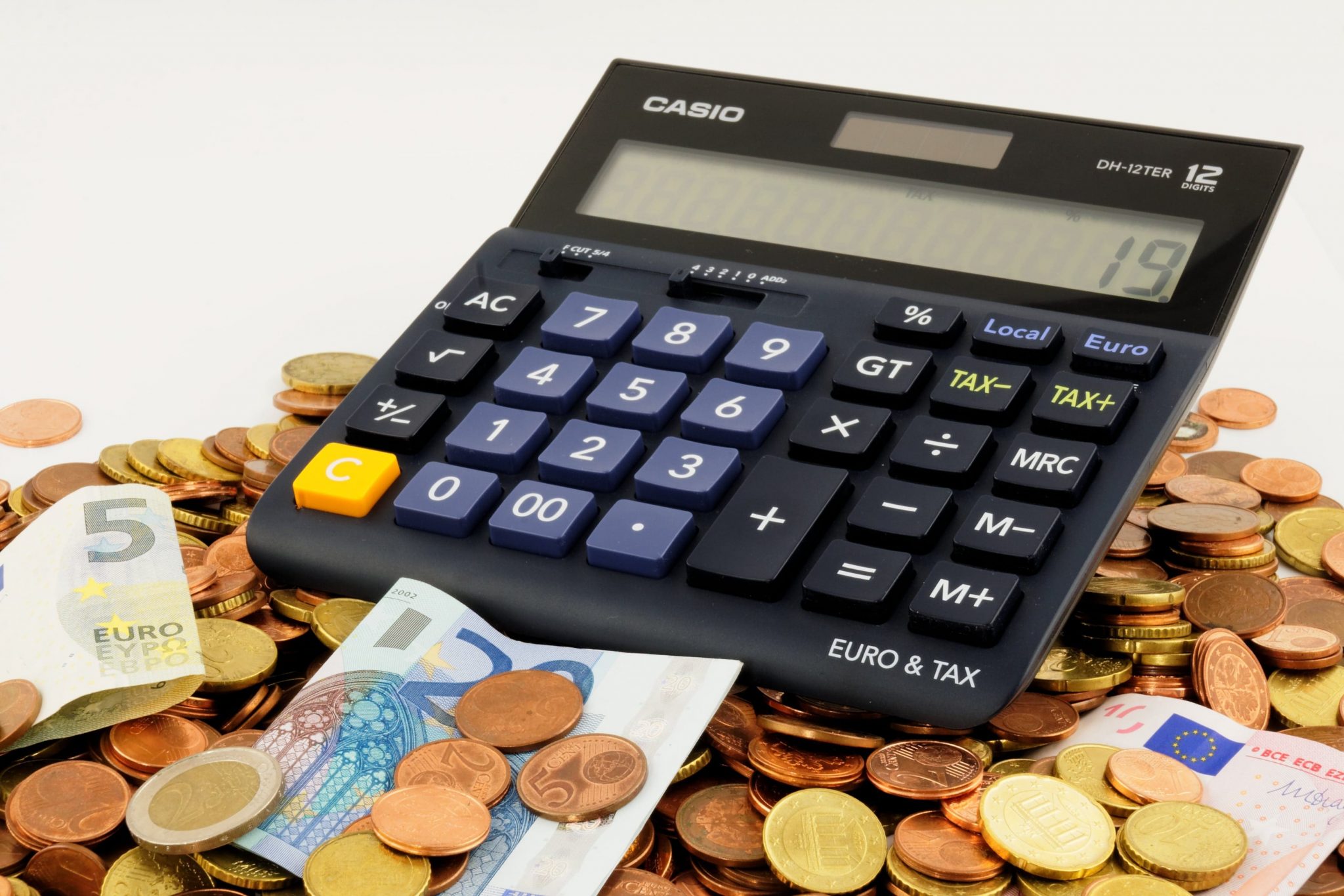  A calculator sits on top of a pile of Euro coins and bills. (Tips for saving money for students).